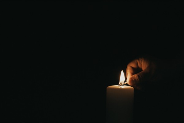 hand lighting single candle in the dark