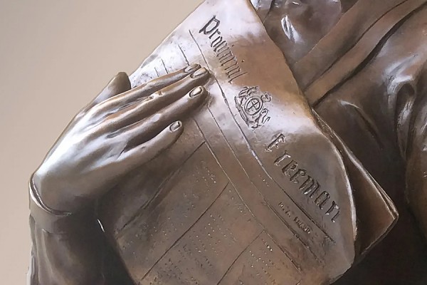 close-up of bronze hands holding Provincial Freeman newspaper