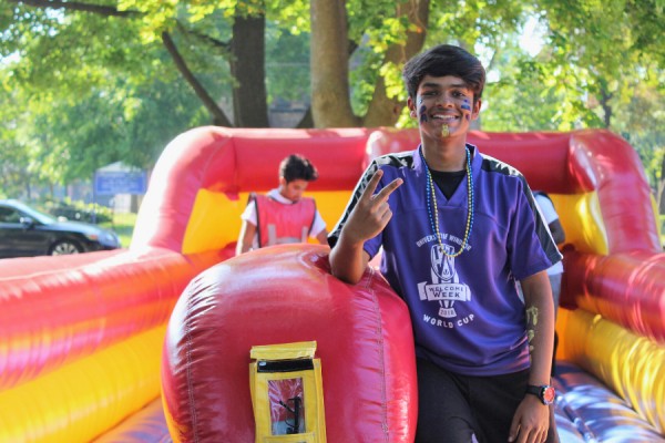 A faculty leader stands next to an orientation obstacle course