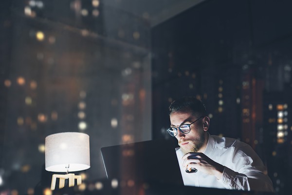 young looking at computer in darkened room