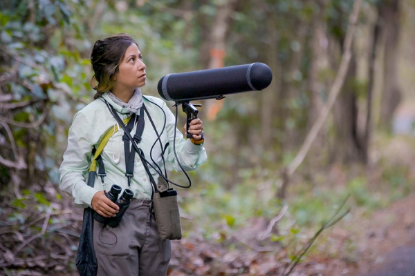 Natalie Sanchez holds large microphone in forest