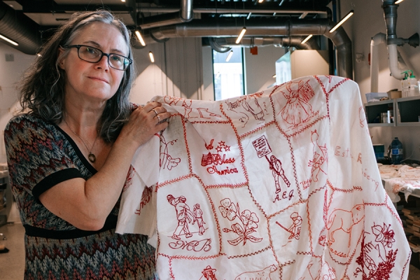 Catherine Heard holds red work quilt