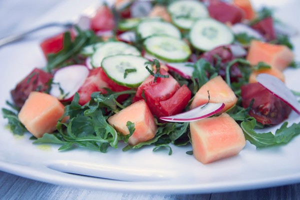 salad of tomatoes, melon, and cucumbers over arugula