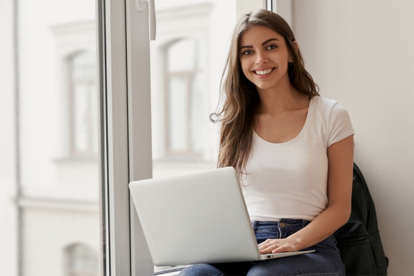 smiling young women types on laptop computer