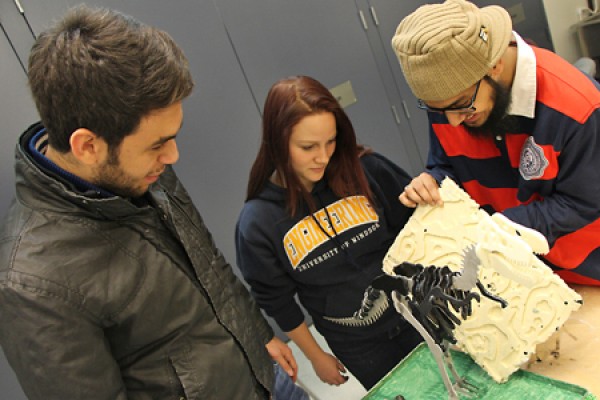 Omar Wasfy, Jordyn McDonald and Usama Saeed look over their model dinosaur