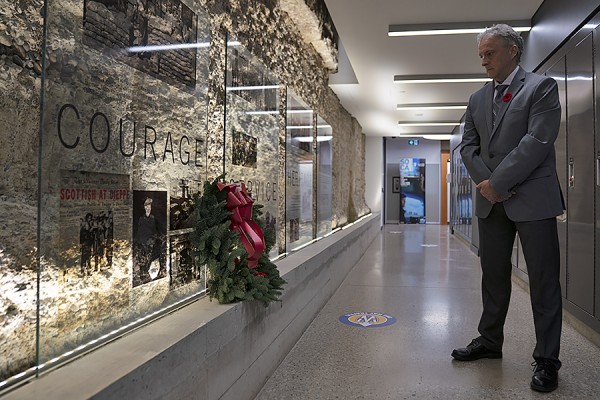 UWindsor president Robert Gordon lays a wreath under a tribute to the courage and sacrifice of those who served.