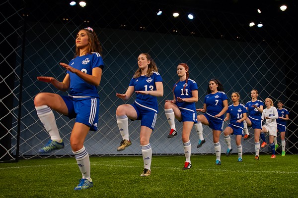 girls in soccer uniforms lined up for warm-up exercises