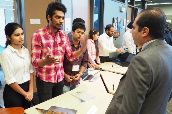 Students Krishna Telapudi, Kameswara Peddada, and Kartik Peddinti discuss their project with professor Pooya Moradian Zadeh during Computer Science Demo Day 2022.