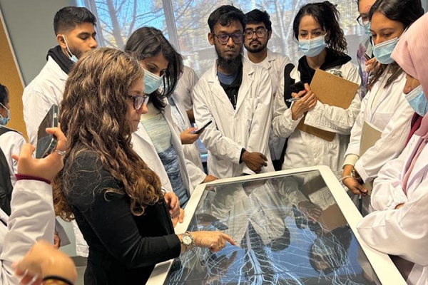 Students crowd around to view a demonstration of a simulated dissection table.