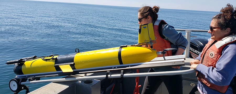 two women prepare to launch underwater drone from boat