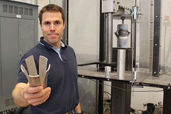 Engineering professor Bill Altenhof holds a metal tube.