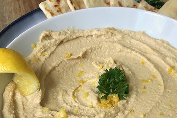 bowl of hummus with wedges of pita bread alongside