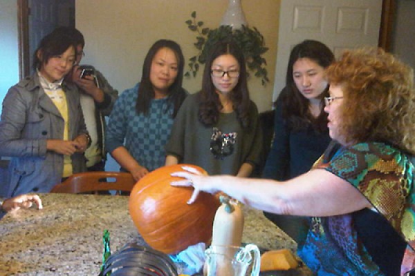 students watch host carve a pumpkin