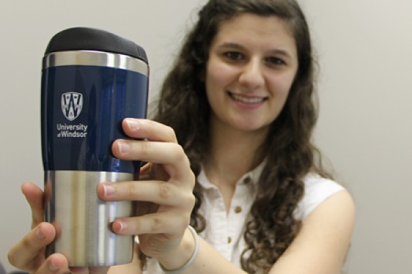 Business student Stephanie Stojkovski holding her new UWindsor travel mug 