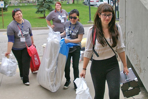 Volunteers help a new student carry her possessions into residence during Move-in Day.