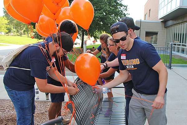 Student volunteers tying balloons to a bench commemorating Jessica Girard