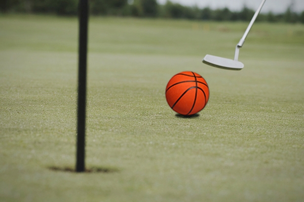 putter directing basketball toward golf hole