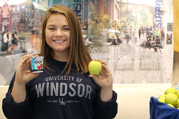 student holding up apple and cup of yogurt