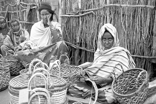 In this photo by Douglas MacLellan, a master basket maker shows her products at the Hagadera Refugee Camp near Dadaab, Kenya.