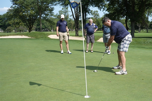 Terry Roman readies a putt watched by competitors Peter Baldwin, John Ropac, and Don Turner