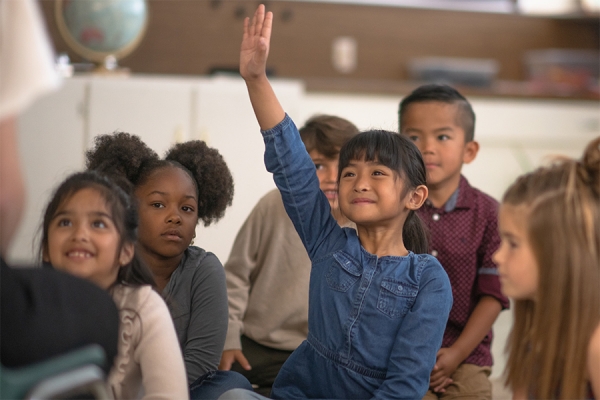 young person raising hand confidently in class