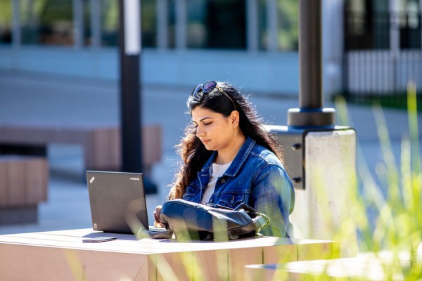A student works on their laptop outside at the University of Windsor.