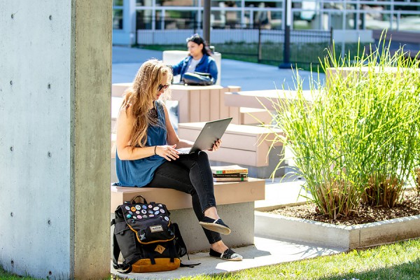 students sitting at distance on campus benches