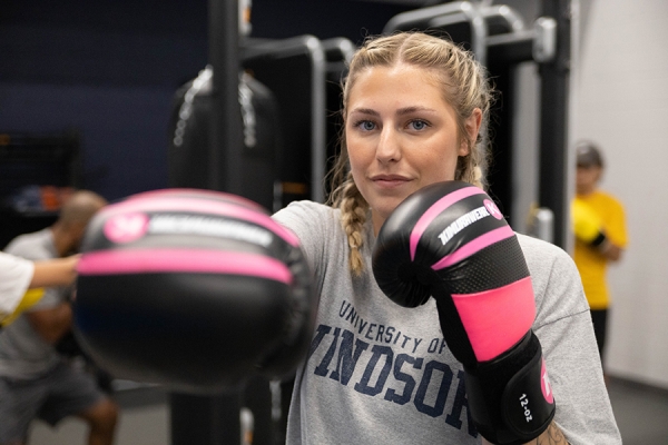 Lauryn Rogers wearing boxing gloves in fitness centre.