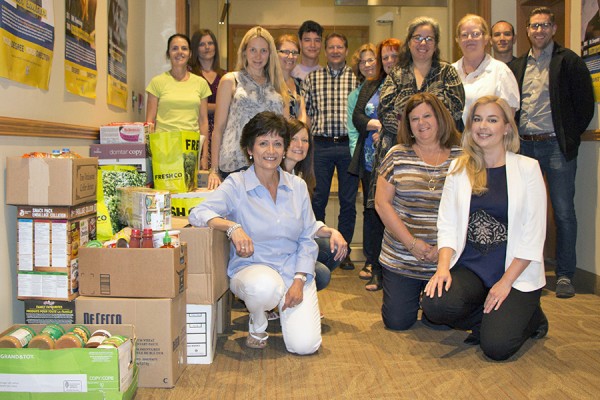 staff posing alongside boxes of canned foods