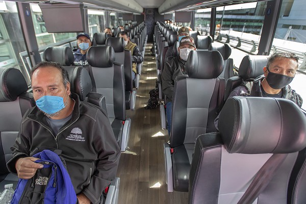 Migrant workers wearing face masks on a bus