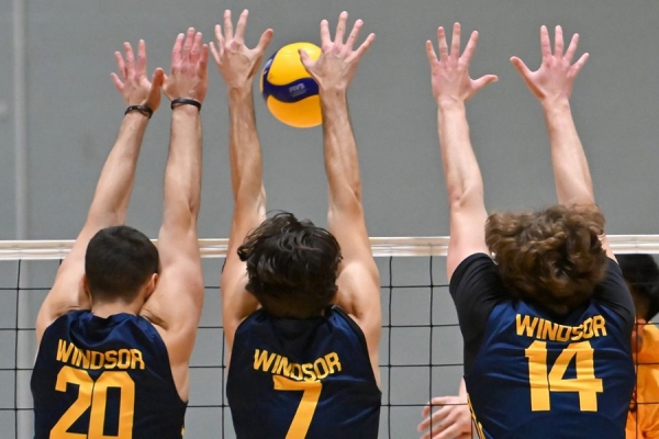 men's volleyball players blocking shot at net
