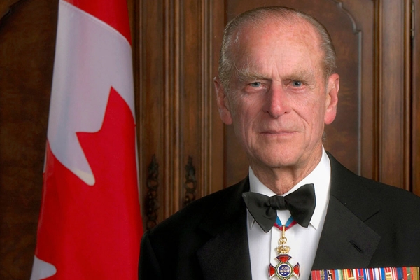 Prince Philip posing before Canadian flag