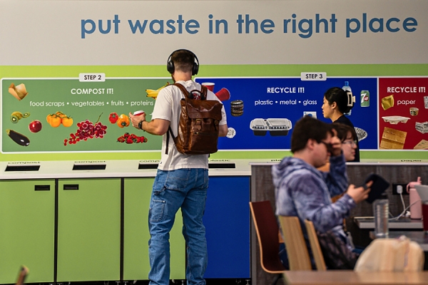 student sorting waste into recycling receptacles