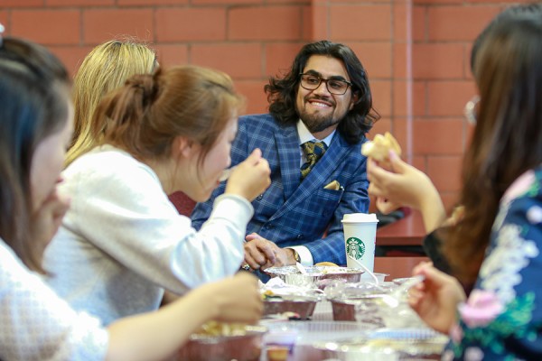 Sam Sinjari sitting at table with students