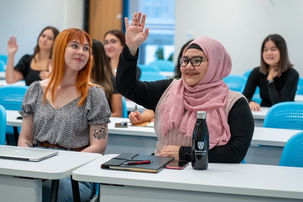 students raising hands in classroom