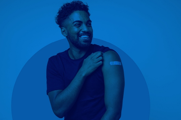 young man rolling up sleeve to show site of his vaccination