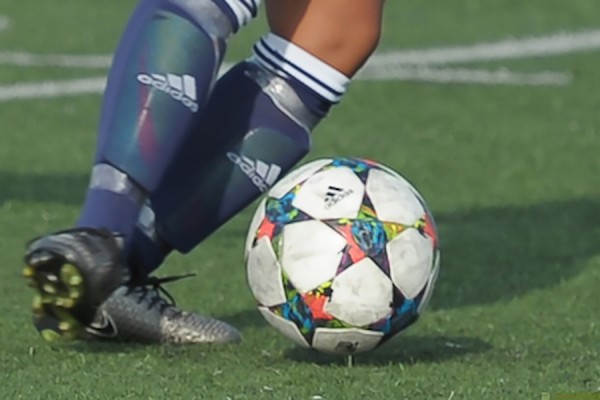 feet in cleats chasing soccer ball