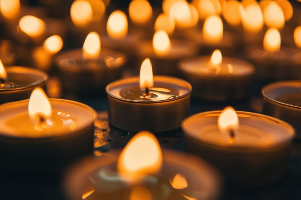 Tea light candles burn against a black background
