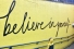 Child standing before billboard "Believe in Yourself"