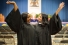 two young women in convocation robes raising hands in celebration