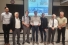 Line up of men; the middle one is holding an award certificate