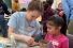 Education student helping young child with craft