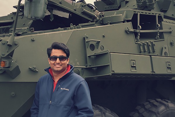 young man posed in front of tank