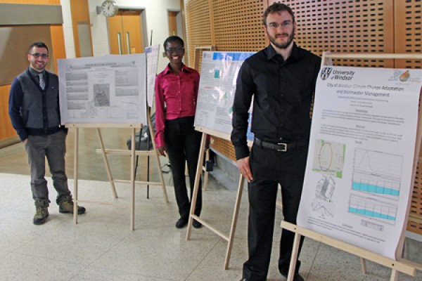 Aojeen Issac, Omotola Ajao, and Rafal Marynowski next to poster boards