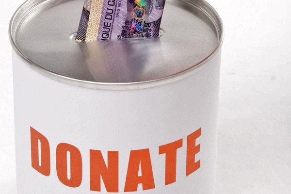 hand depositing banknote into can marked &quot;Donate&quot;
