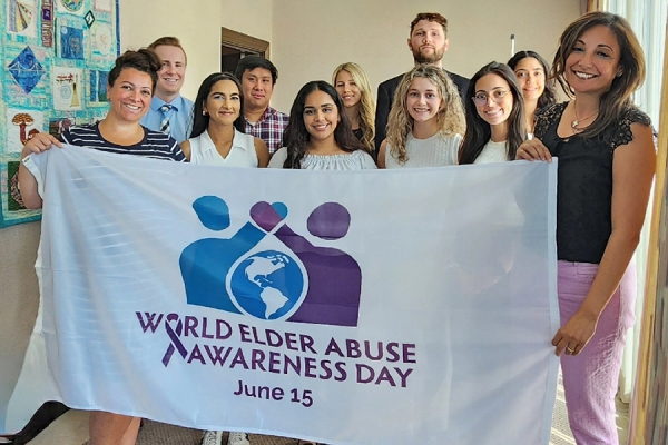 Students hold banner reading “world elder abuse awareness day.”