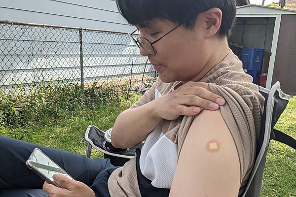 Haesung Ahn shows off upper-arm site of his vaccination.