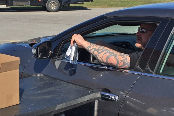 man reaches for bottles through open car window