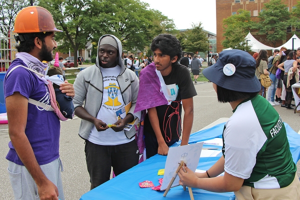 Ali Haider, Joel Effah, and Mohammad Nasir learn about Students Supporting Seniors from volunteer Victoria Doan.