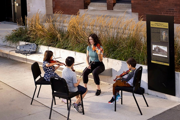 woman instructing children playing violin